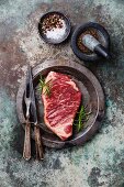 Raw fresh meat Striploin Steak and spices in mortar on metal background