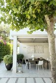 Sommerliche Terrasse mit schwarzem Tisch und weissen Stühlen