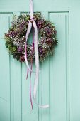 Autumnal wreath with pink lace ribbons on vintage wooden door