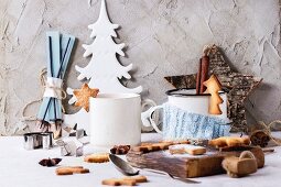 Zwei Tassen mit heißem Tee und Weihnachtsplätzchen, Puderzucker und Weihnachtsdeko auf Tisch