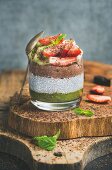 Matcha, almond milk, cocoa chia seed pudding with fresh fruit, berries, mint, chocolate in glass