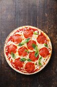 Pepperoni Pizza with basil leaves on wooden table