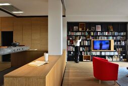 Offenes Wohnen mit moderner Holzküche und schwarzem Metall-Bücherregal mit integiertem Fernseher