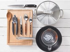Various kitchen utensils: pot, pan, measuring cup, spoon, knife, can opener