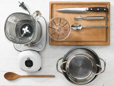 Various kitchen utensils: blender, pots, a measuring cup, spoon, knife