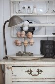 Eggs on metal stand on chest of drawers below plate rack on wall