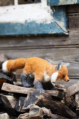 Hand-made, felted, woollen fox on firewood