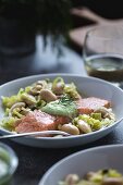 A plate full of white butter beans topped with oven baked salmon slices