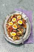 Brown lentil, potatoes and sausage salad with bacon and eggs