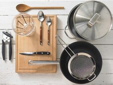 Various kitchen utensils: pot, pan, sieve, measuring cup, can opener