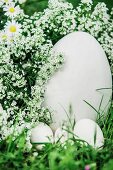 White eggs of different sizes and white flowers amongst grass