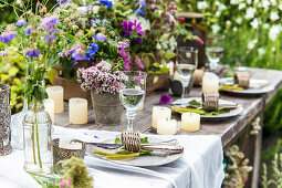 Gedeckter Tisch mit Wiesenblumen und Kerzen im Garten
