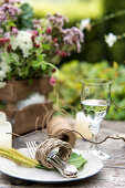 Cutlery in wicker napkin ring on rustic garden table