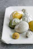 Verschiedene Eier mit Liebesperlen verziert auf weißer Porzellanplatte
