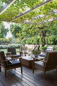 Upholstered wooden armchairs under the overgrown pergola