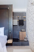 Steps leading to small bathroom behind black partition wall with bed in foreground