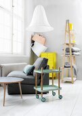 Hostess trolley, easy chair, neon-yellow chest of drawers and ladder shelving in modern, Nordic interior