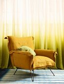 Yellow armchair in front of yellow ombré curtain