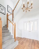 A staircase with a grey carpet in a hallway in front of a white lattice door