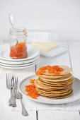 Pancakes with red caviar on white wooden background