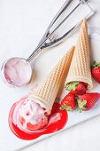 Wafer cones with strawberry ice cream with syrup, mint and fresh strawberries