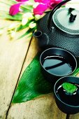 Asiatischer Tee in Schälchen und Teekanne auf Holztisch
