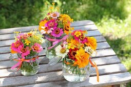 Bunte Blumensträusse mit Zinnias und Tagetes auf rustikalem Gartentisch