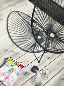 Magazines, glass of wine and black retro chair on wooden terrace