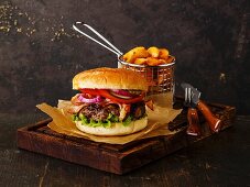 Burger with meat and potato wedges on dark background