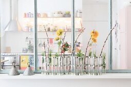 Flower arrangement against interior window with view into kitchen