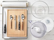 Various kitchen utensils: blender, glass bowls, knives, spoons, peeler