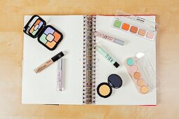 Verschiedene Kosmetikprodukte für Color-Correcting auf einem Ringbuch