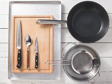 Various kitchen utensils: pan, pot, strainer, oven tray, knife, spoon