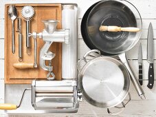 Various kitchen utensils: meat grinder, pasta machine, pots, pan