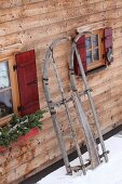 Rustic wooden sledge leaning against façade of wooden cabin