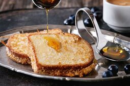 Grilled Toasts with pouring honey, blueberries and cup of coffee espresso, served on vintage tray