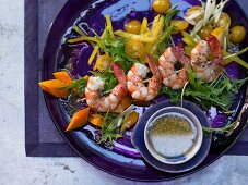 Prawn skewers on salad with a lime and ginger sauce and sesame seeds