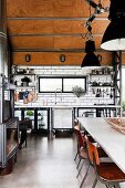 Open kitchen in industrial style, with concrete floor, subway tiles and wood-clad ceiling