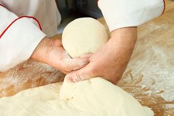 A piece of soft dough being twisted off by hand