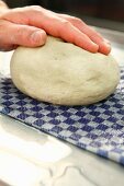 Dough being rolled over a wet cloth to moisten it