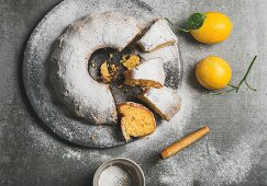 Homemade gluten-free lemon bundt cake with sugar powder served with freshly picked lemons