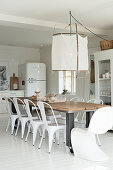 Long dining table and white chairs in open-plan kitchen