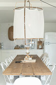 Large ceiling lamp above long dining table in open-plan kitchen