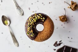 Ein schwebender Donut mit Schokoladenglasur und Pistazien