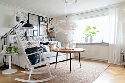 weiße Möbel im hellen Wohnzimmer mit Bilderwand und Schaukelstuhl