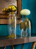 Glass covers over sycamore leaves on console table