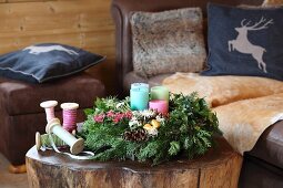 Advent arrangement with four candles on tree-stump coffee table