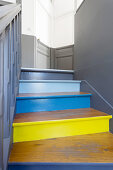 Old wooden staircase with brightly painted risers and bicoloured walls and doors