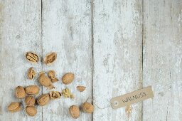 Walnuts with a brown paper label on a wooden background (top view)