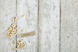 Cashew nuts with a brown paper label on a wooden background (top view)